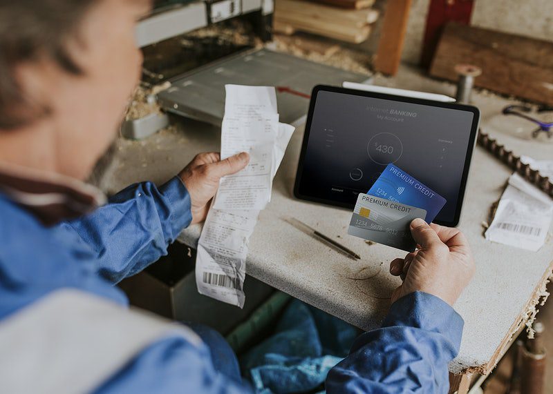 Senior business owner holding his credit cards with tablet on the desk